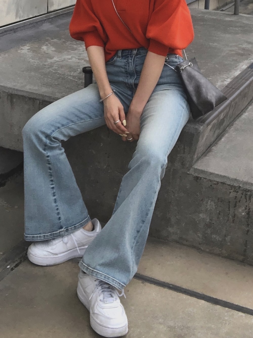 オレンジ系のポロシャツ、ブルー系のデニムパンツ、ホワイト系のスニーカーを着用したレディースの夏コーディネートの4枚目の写真