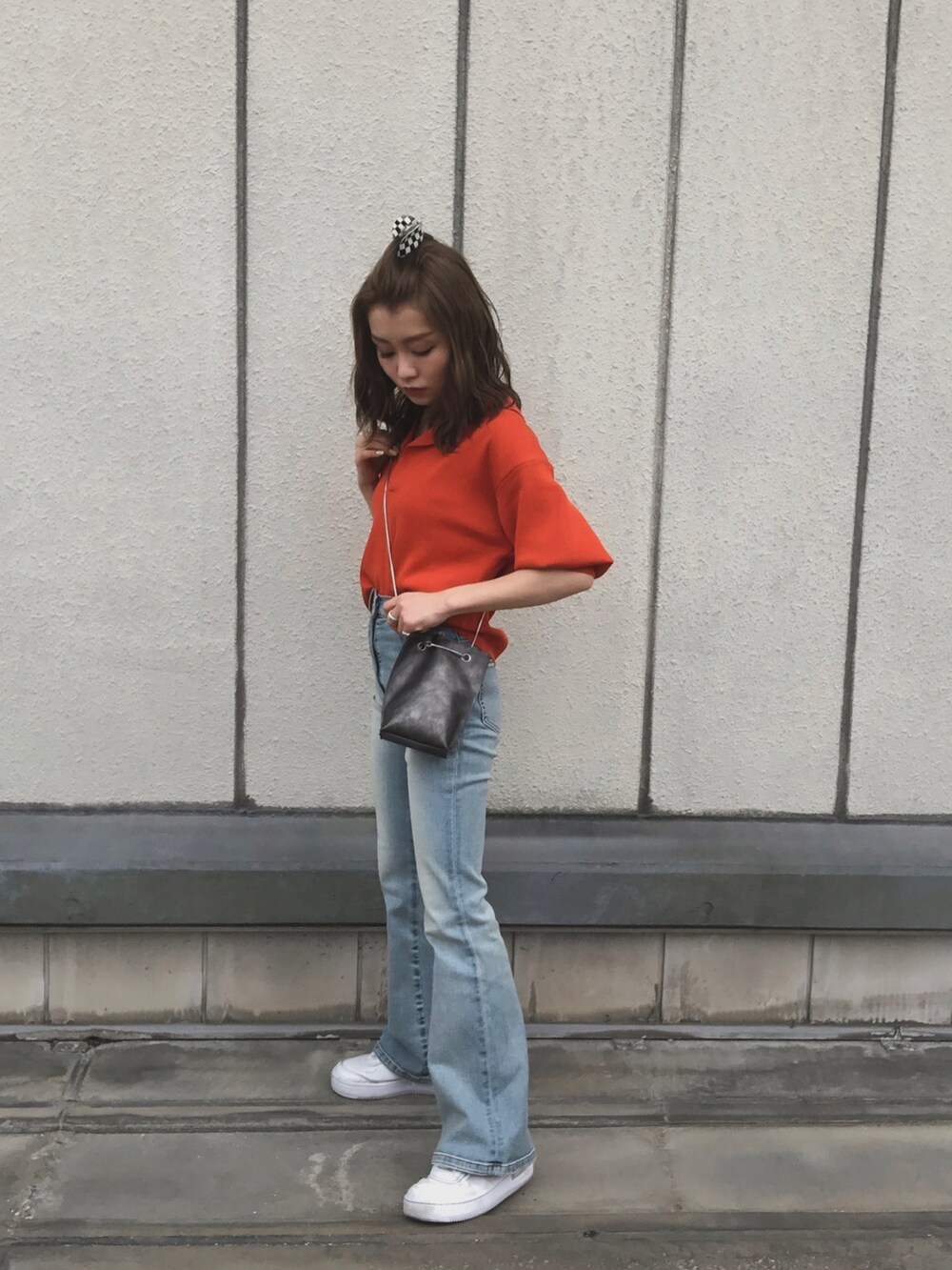 オレンジ系のポロシャツ、ブルー系のデニムパンツ、ホワイト系のスニーカーを着用したレディースの夏コーディネートの2枚目の写真