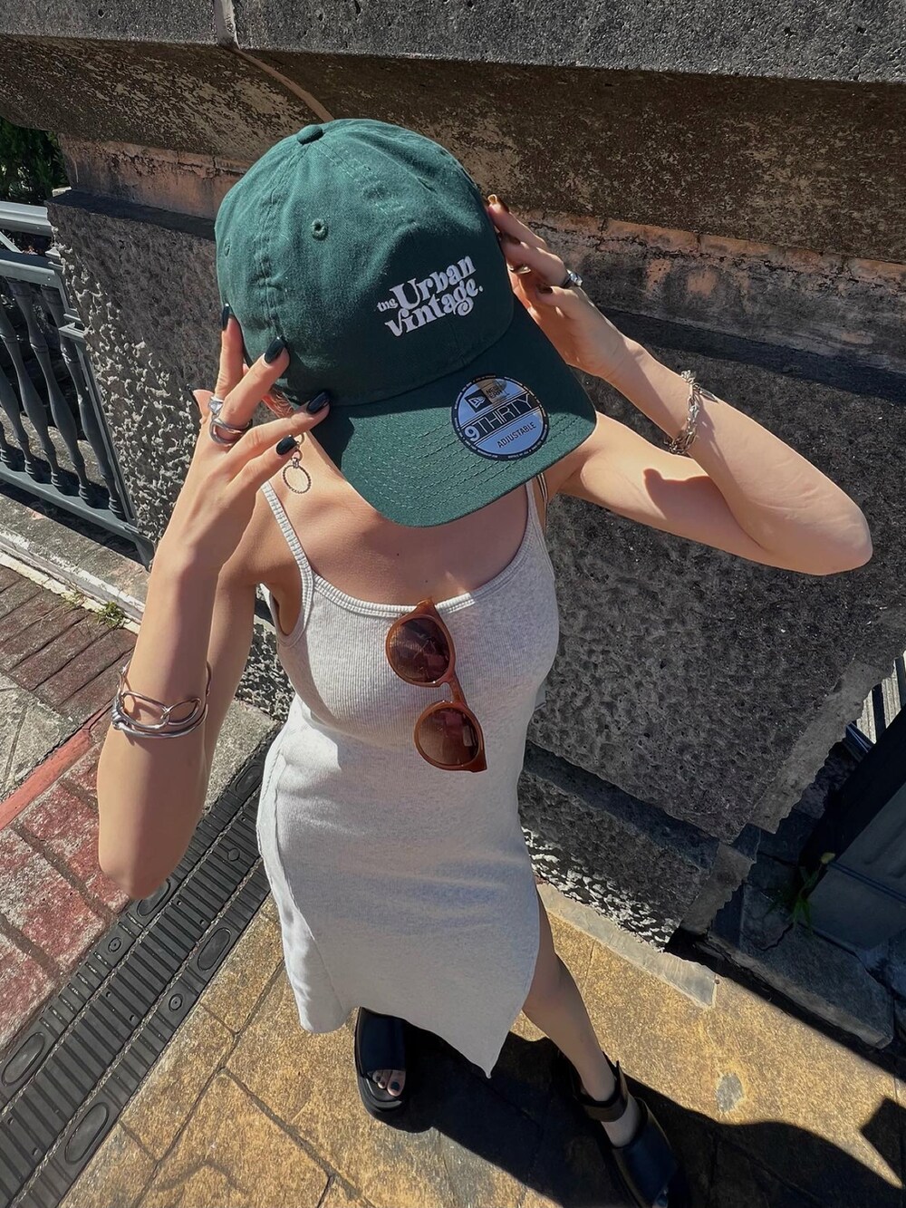 グレー系のワンピース、ブラック系のサンダル、グリーン系のキャップを着用したレディースの夏コーディネートの2枚目の写真
