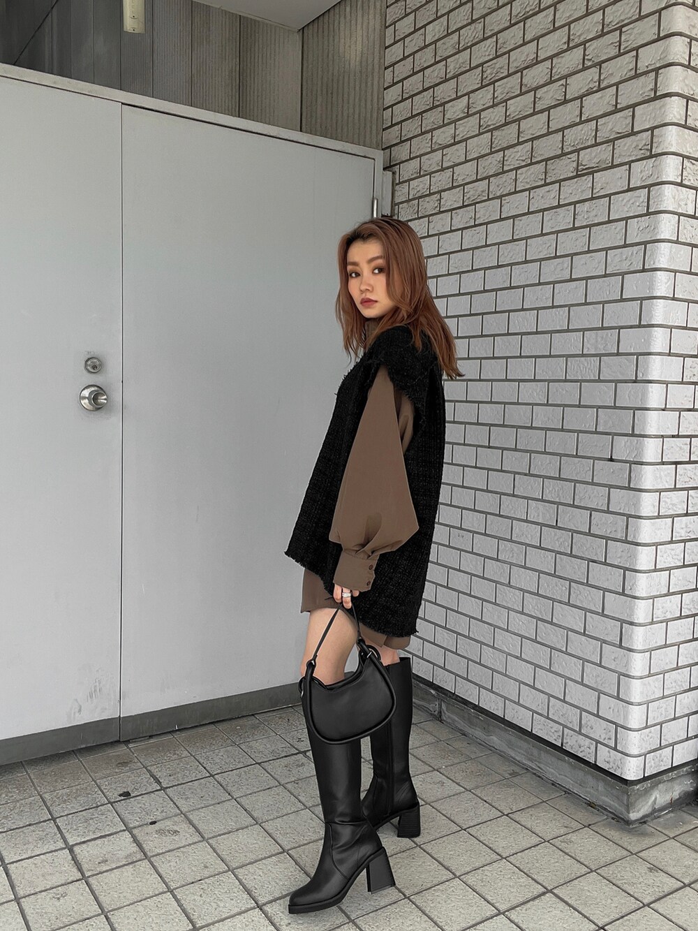 ブラック系のワンピース、ブラック系のブーツ、ブラック系のハンドバッグを着用したレディースの秋コーディネートの2枚目の写真