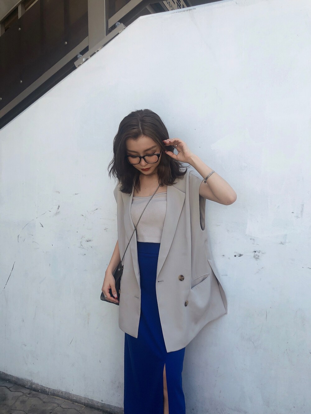 ブルー系のスカート、ホワイト系のキャミソール、ベージュ系のベストを着用したレディースの夏コーディネートの3枚目の写真