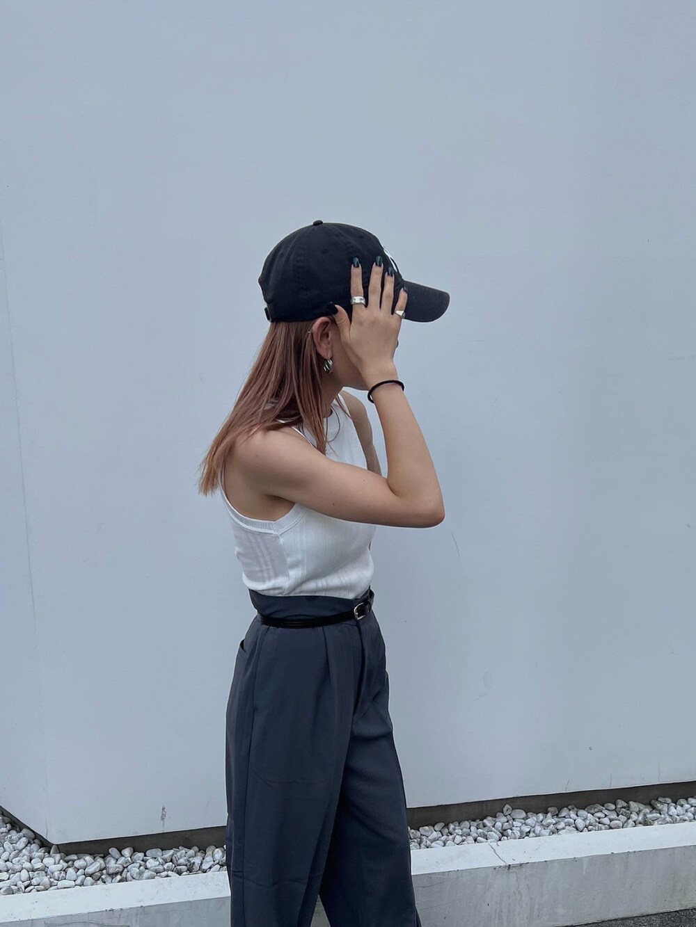 グレー系のスラックス、ホワイト系のタンクトップ、ホワイト系のスニーカーを着用したレディースの夏コーディネートの3枚目の写真