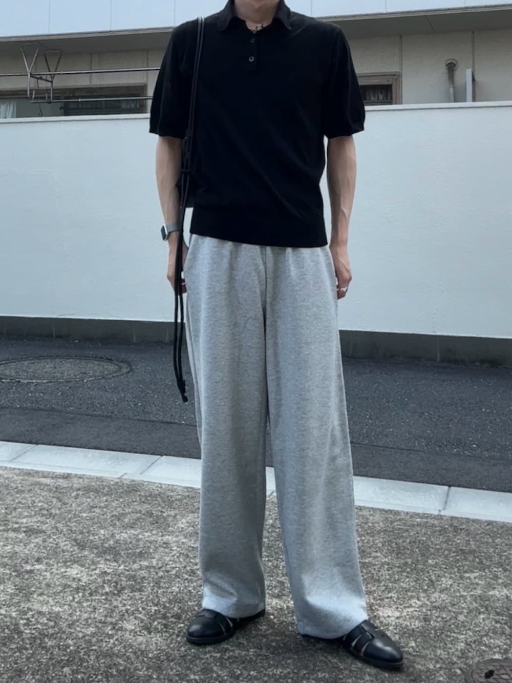 ブラック系のポロシャツ、グレー系のスウェットパンツ、ブラック系のサンダルを着用したメンズの夏コーディネートの2枚目の写真