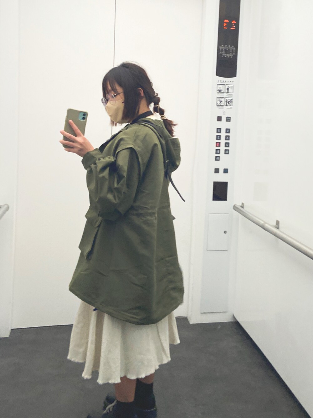 ホワイト系のジャケット/アウター、グリーン系のマウンテンパーカー、ブラック系のドレスシューズを着用したレディースの春コーディネートの2枚目の写真