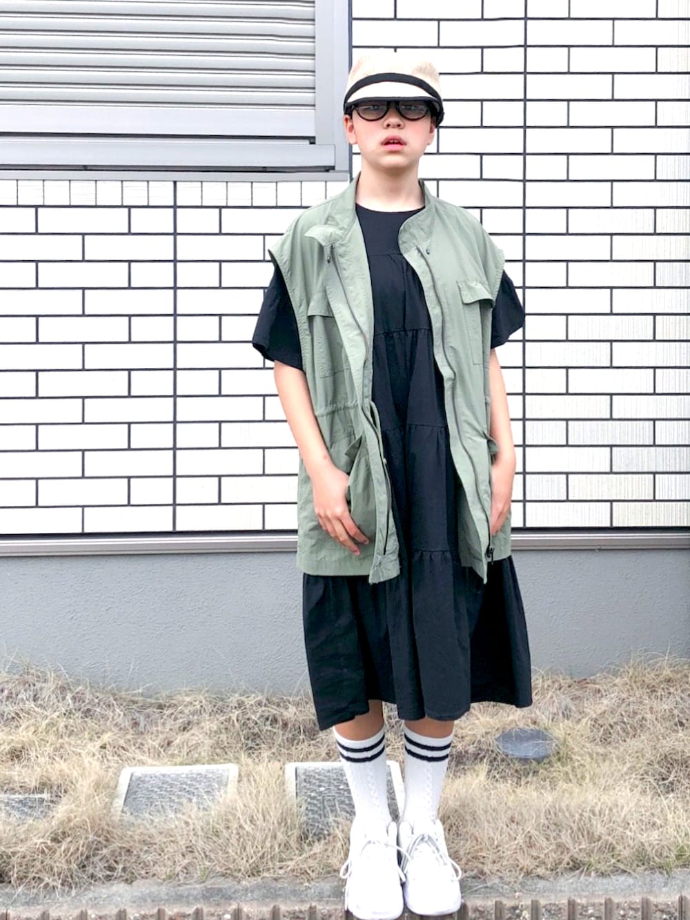 グリーン系のベスト、ブラック系のワンピース、ホワイト系のスニーカーを着用したキッズの春コーディネートの2枚目の写真