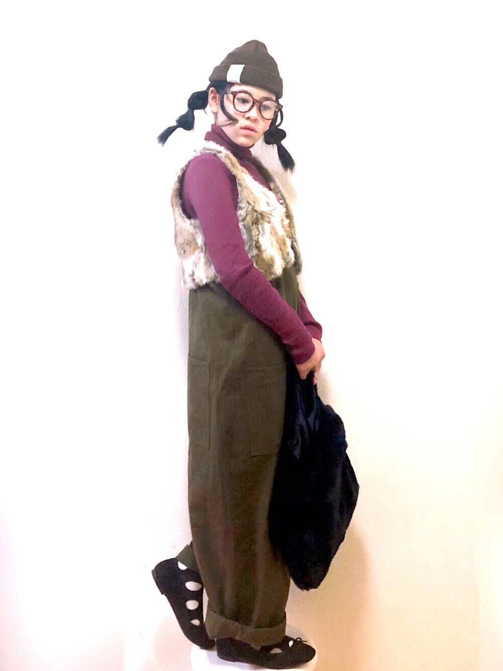 パープル系のニット/セーター、ブラウン系のベスト、ブラウン系のジャンパースカートを着用したキッズの冬コーディネートの2枚目の写真