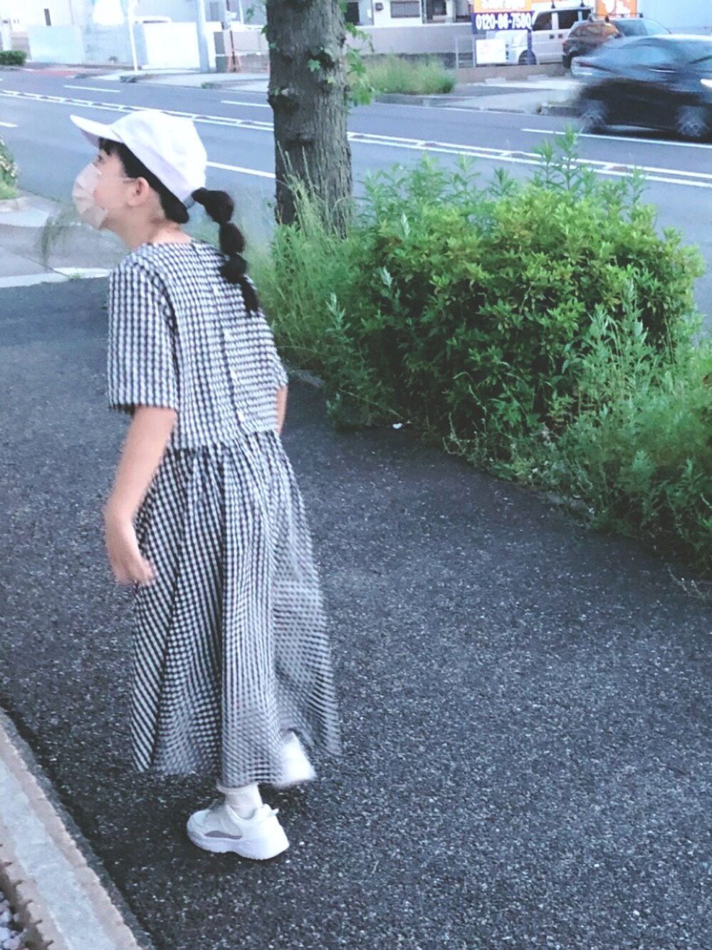 ブラック系のワンピース、ベージュ系のかごバッグ、ホワイト系のパンプスを着用したキッズの春コーディネートの3枚目の写真