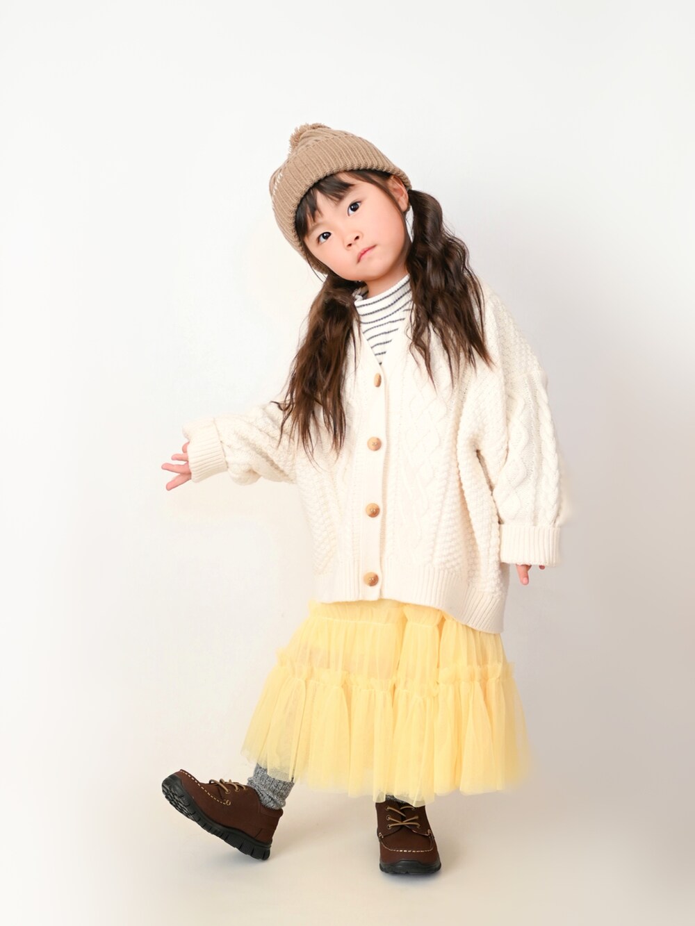 ホワイト系のTシャツ/カットソー、ホワイト系のカーディガン/ボレロ、イエロー系のスカートを着用したキッズの冬コーディネートの2枚目の写真