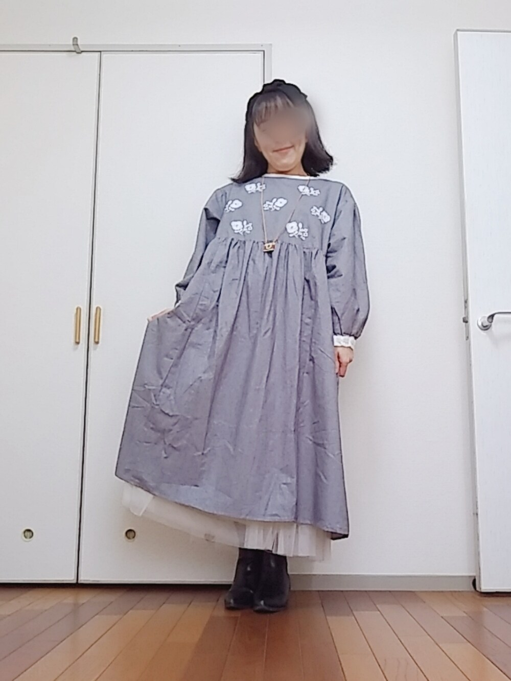 グレー系のワンピース、ブラック系のブーツ、ホワイト系のスカートを着用したレディースの秋コーディネートの2枚目の写真