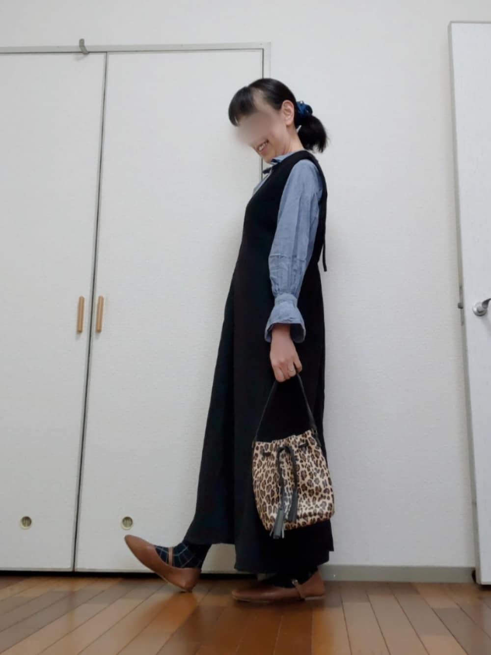 ベージュ系のバッグ、ブラック系のジャンパースカート、ブルー系のシャツ/ブラウスを着用したレディースの春コーディネートの2枚目の写真