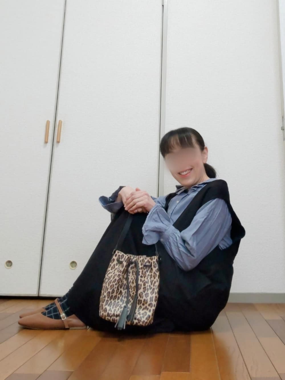 ベージュ系のバッグ、ブラック系のジャンパースカート、ブルー系のシャツ/ブラウスを着用したレディースの春コーディネートの3枚目の写真