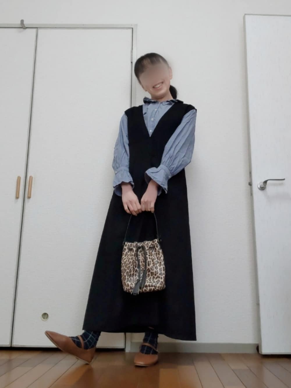 ベージュ系のバッグ、ブラック系のジャンパースカート、ブルー系のシャツ/ブラウスを着用したレディースの春コーディネートの4枚目の写真