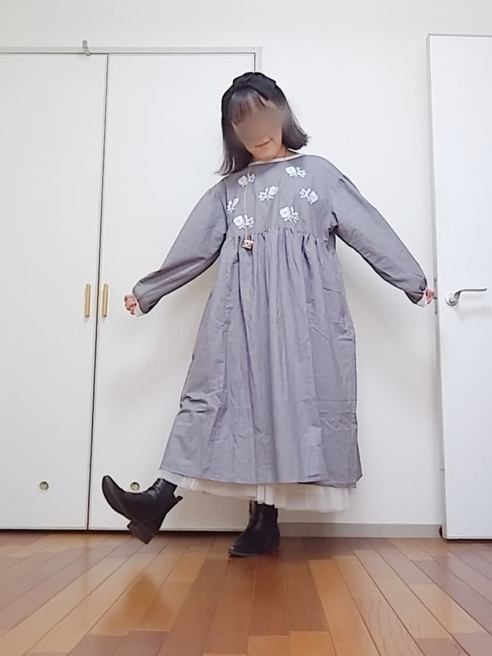 グレー系のワンピース、ブラック系のブーツ、ホワイト系のスカートを着用したレディースの秋コーディネートの3枚目の写真