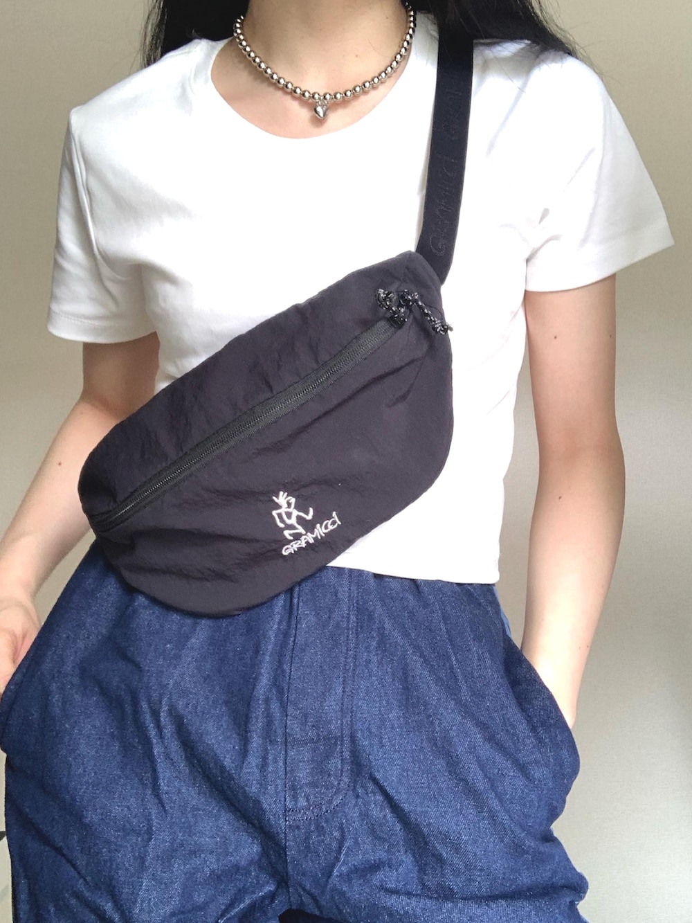 ブルー系のデニムパンツ、ブラック系のボディバッグ/ウエストポーチ、ホワイト系のTシャツ/カットソーを着用したレディースの夏コーディネートの3枚目の写真