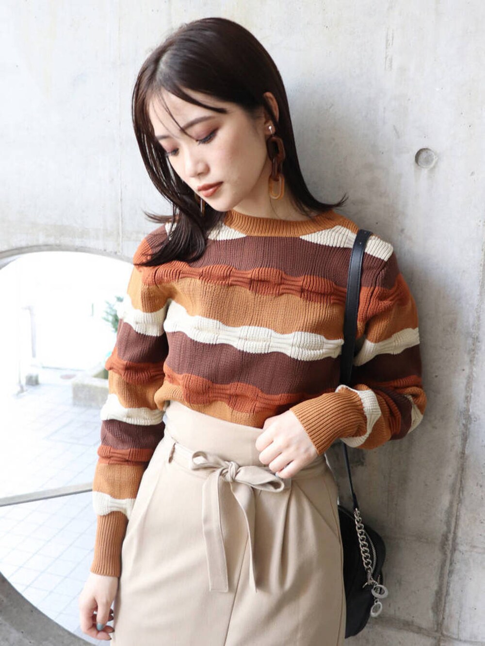 ブラック系のショルダーバッグ、ブラック系のローファー、ブラウン系のニット/セーターを着用したレディースの冬コーディネートの2枚目の写真