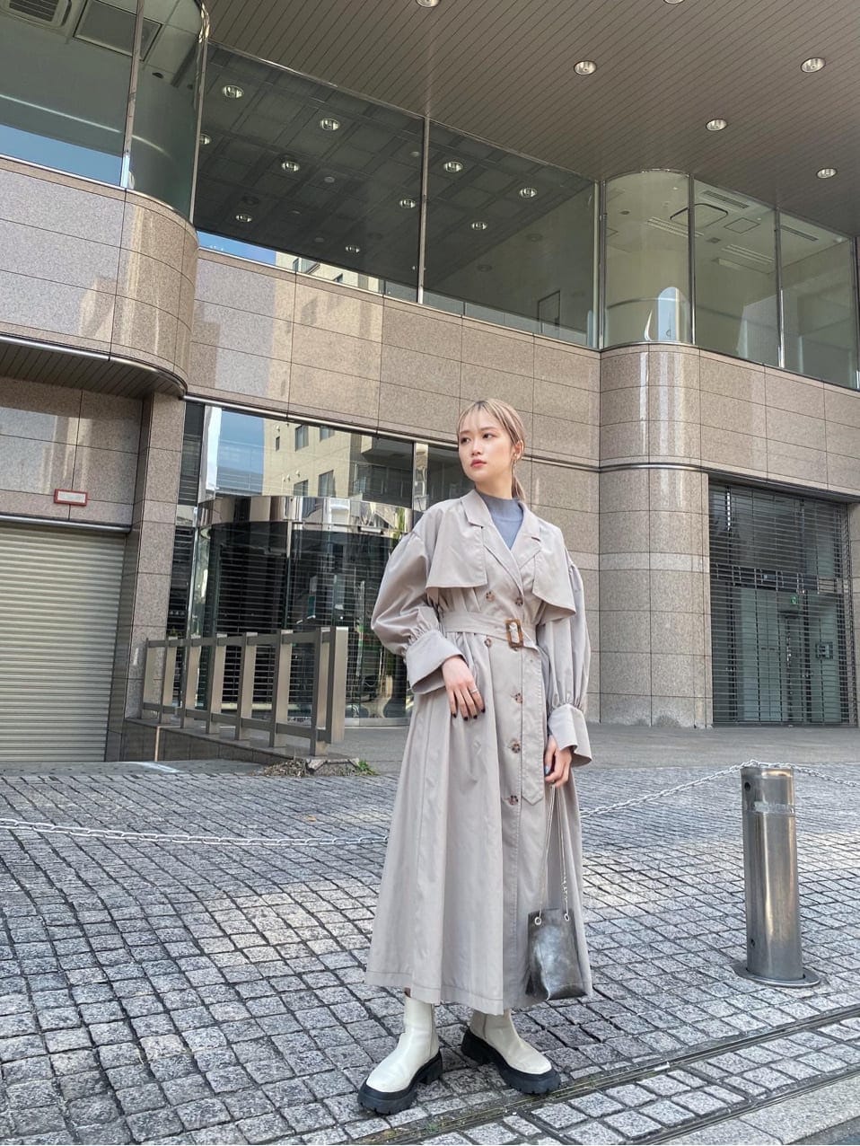 ベージュ系のトレンチコート、ホワイト系のブーツ、ブラック系のショルダーバッグを着用したレディースの春コーディネートの6枚目の写真