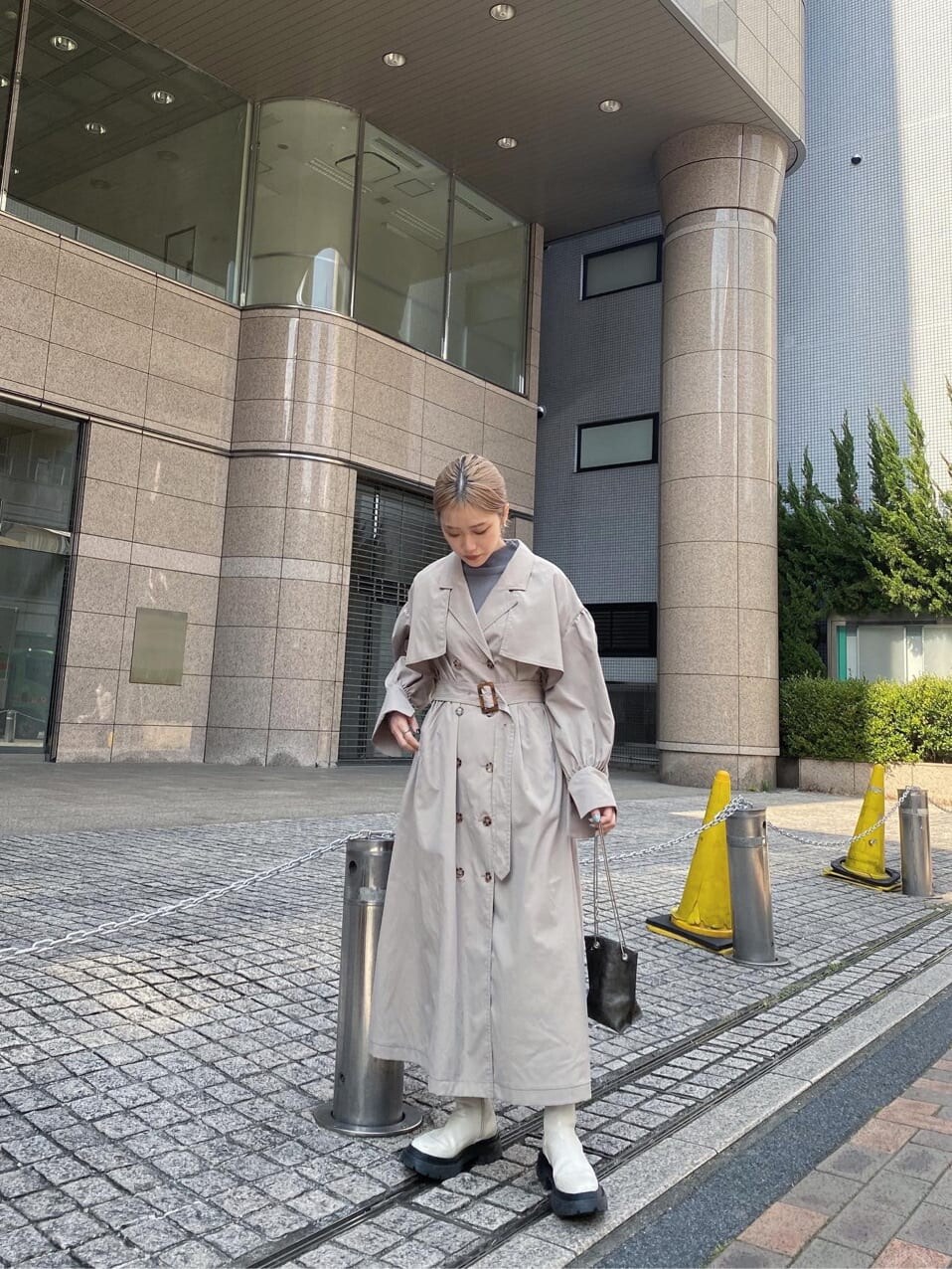 ベージュ系のトレンチコート、ホワイト系のブーツ、ブラック系のショルダーバッグを着用したレディースの春コーディネートの5枚目の写真