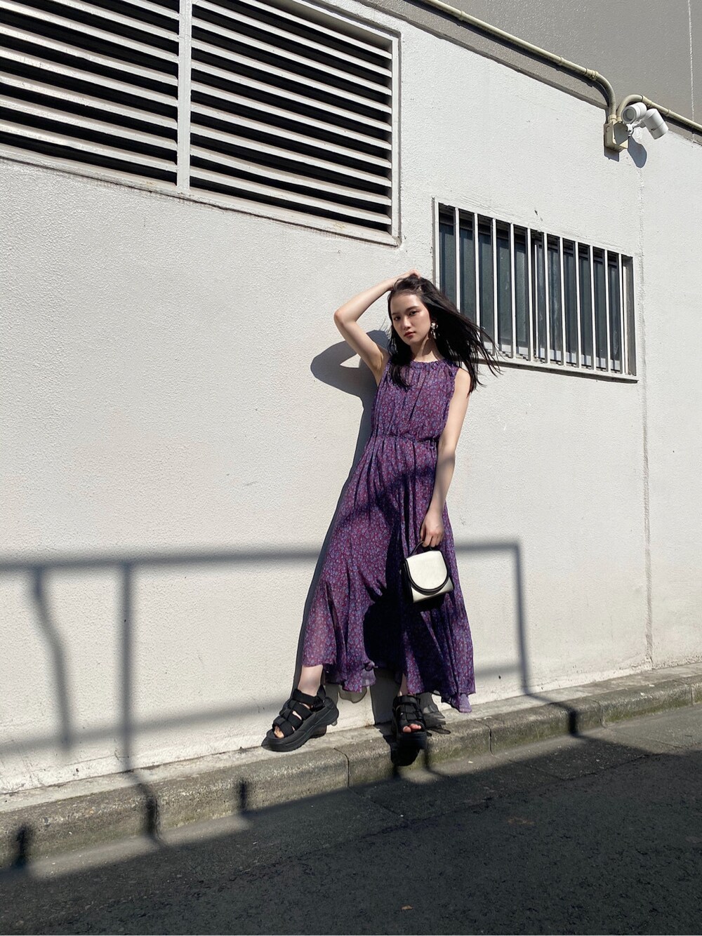 パープル系のワンピース、ブラック系のサンダル、ゴールド系のイヤリングを着用したレディースの夏コーディネートの4枚目の写真