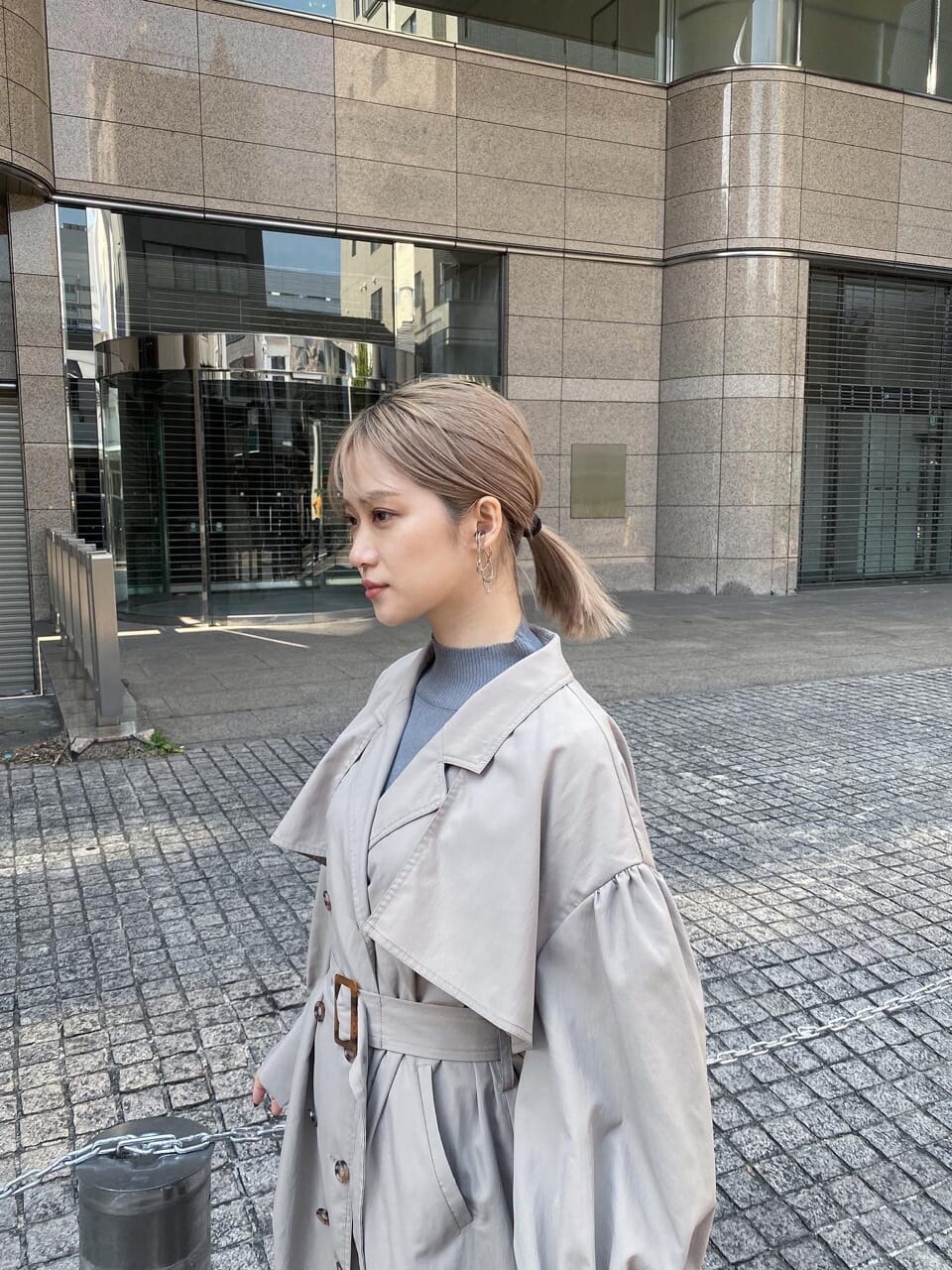 ベージュ系のトレンチコート、ホワイト系のブーツ、ブラック系のショルダーバッグを着用したレディースの春コーディネートの4枚目の写真