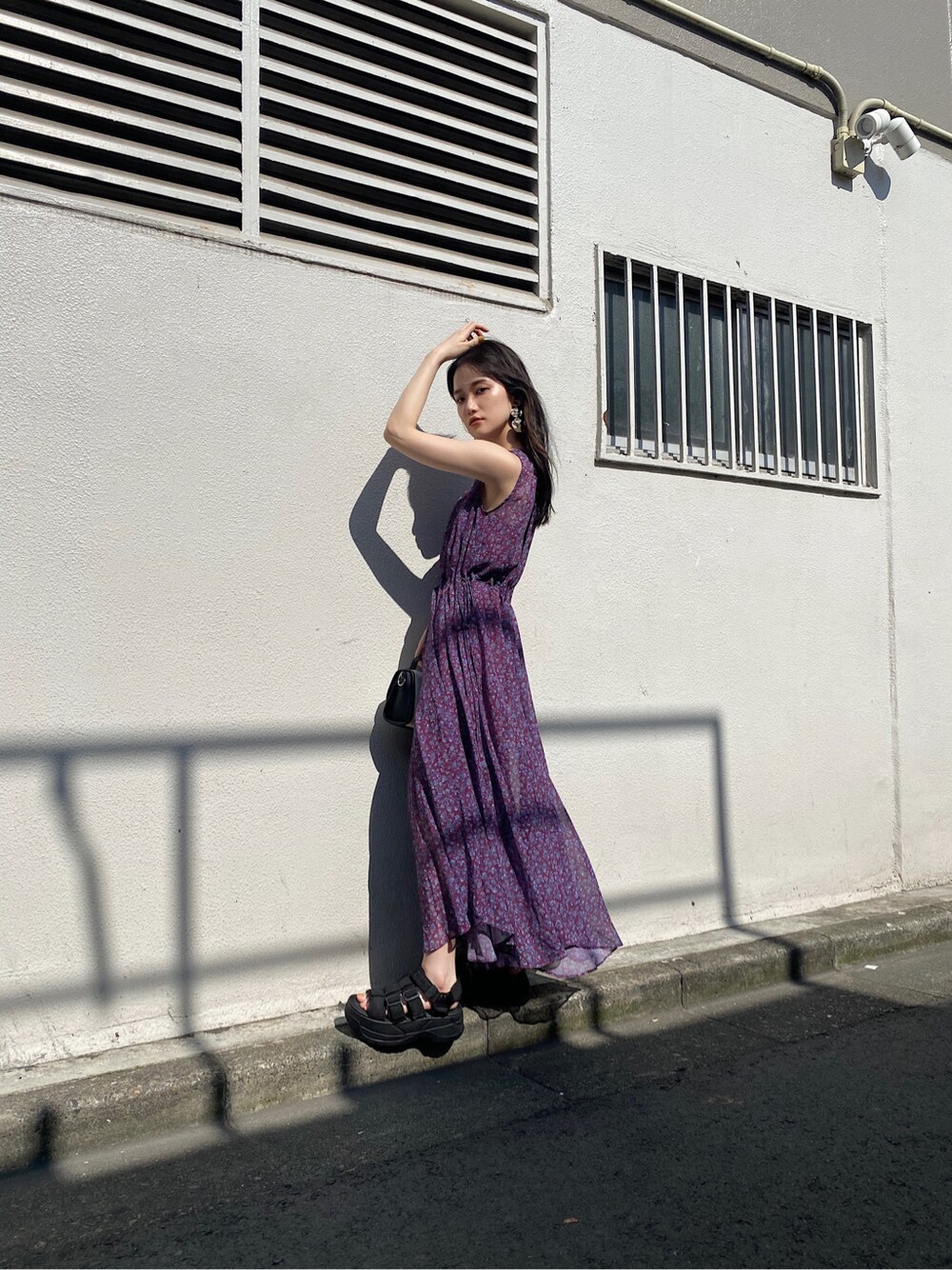 パープル系のワンピース、ブラック系のサンダル、ゴールド系のイヤリングを着用したレディースの夏コーディネートの3枚目の写真