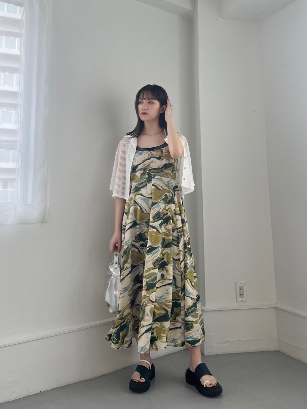 グリーン系のワンピース、ホワイト系のトップス、シルバー系のハンドバッグを着用したレディースの冬コーディネートの4枚目の写真