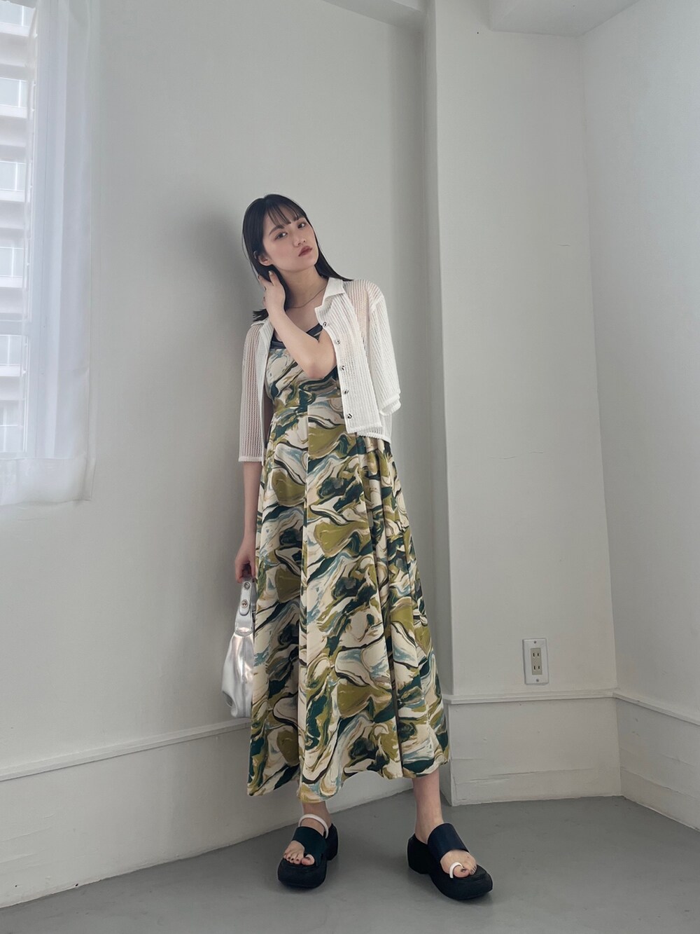 グリーン系のワンピース、ホワイト系のトップス、シルバー系のハンドバッグを着用したレディースの冬コーディネートの5枚目の写真