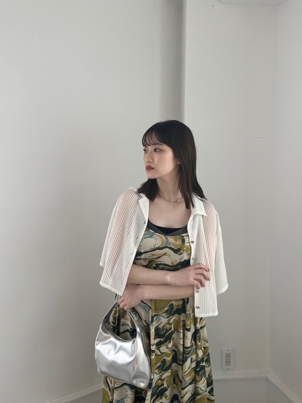 グリーン系のワンピース、ホワイト系のトップス、シルバー系のハンドバッグを着用したレディースの冬コーディネートの3枚目の写真