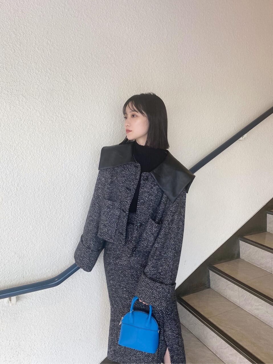 ブラック系のブーツ、ブルー系のハンドバッグ、ブラック系のスカートを着用したレディースの秋コーディネートの5枚目の写真