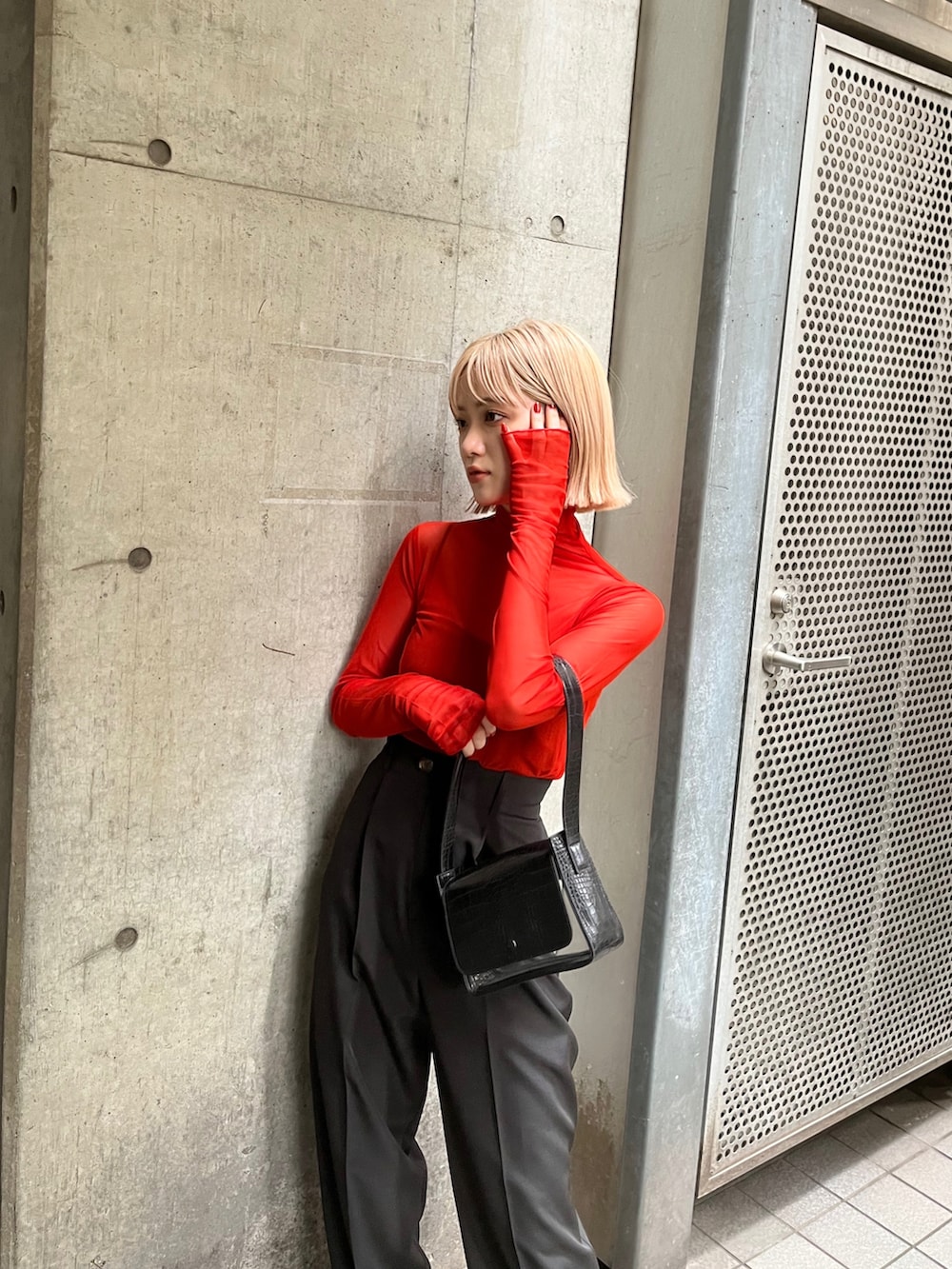 オレンジ系のTシャツ/カットソー、ブラック系のバッグ、ブラック系のスラックスを着用したレディースの夏コーディネートの3枚目の写真