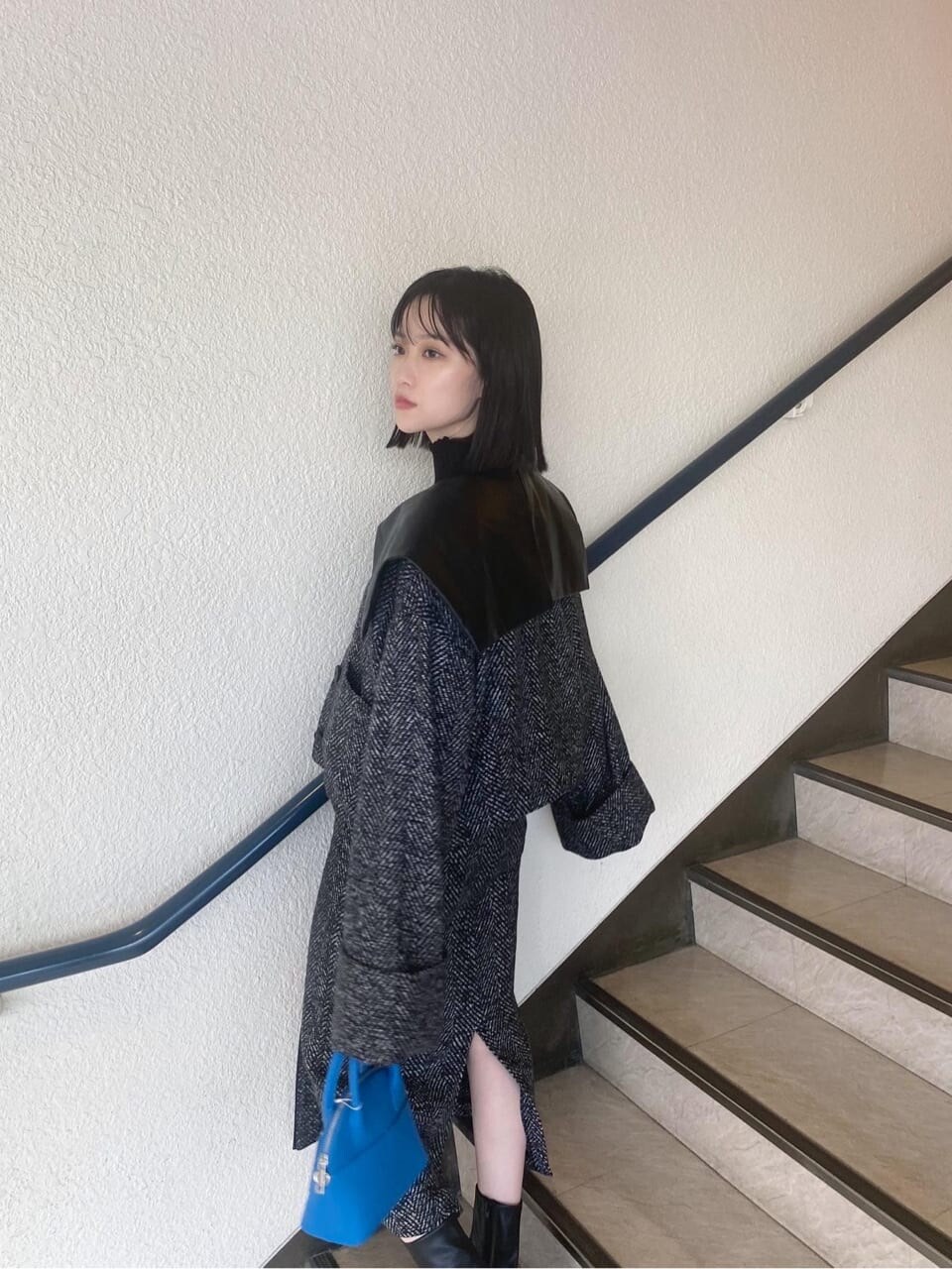 ブラック系のブーツ、ブルー系のハンドバッグ、ブラック系のスカートを着用したレディースの秋コーディネートの4枚目の写真