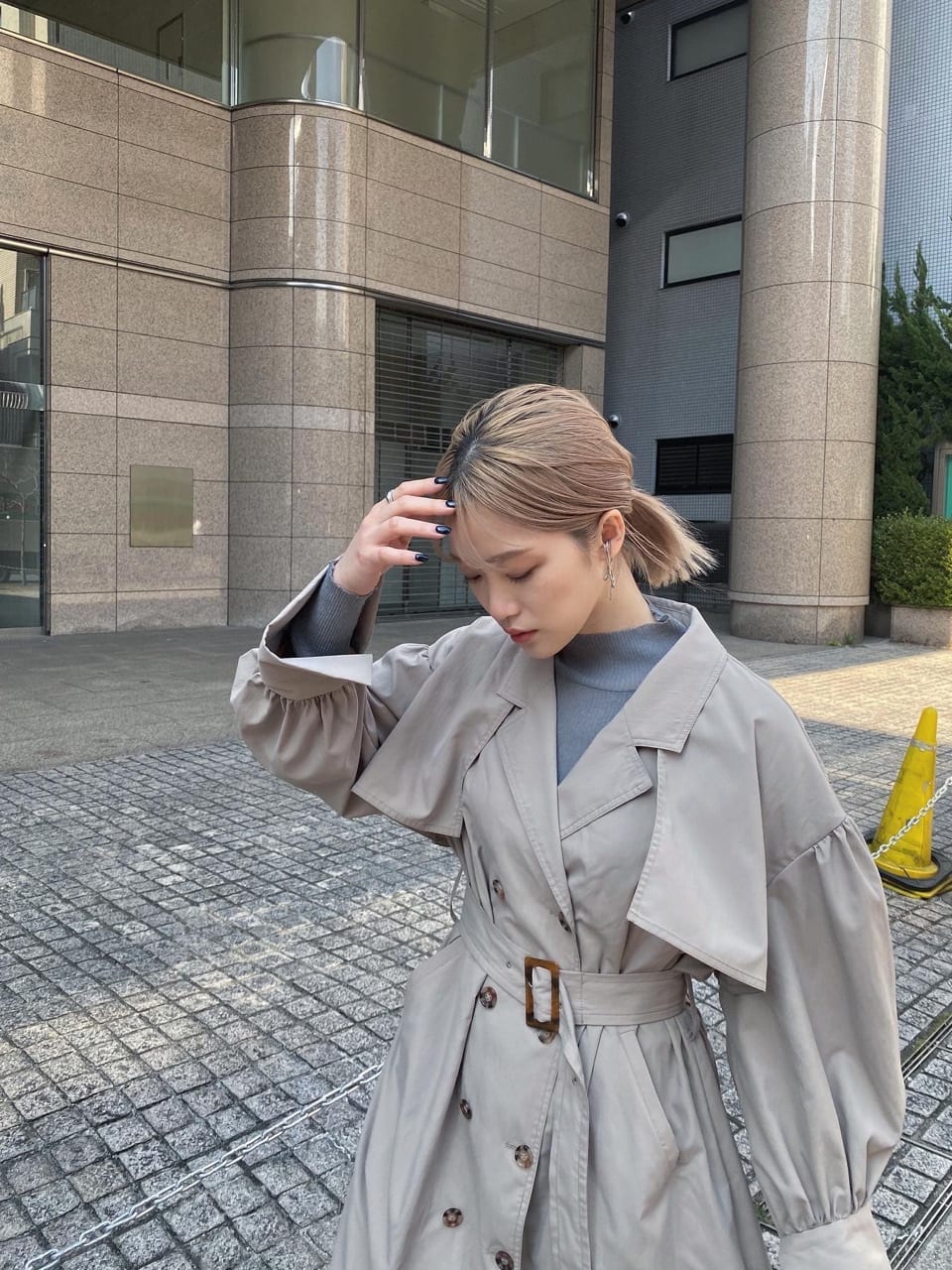 ベージュ系のトレンチコート、ホワイト系のブーツ、ブラック系のショルダーバッグを着用したレディースの春コーディネートの3枚目の写真