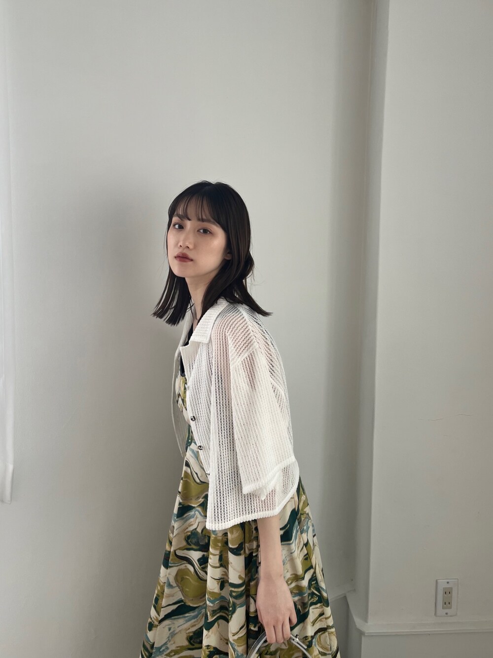 グリーン系のワンピース、ホワイト系のトップス、シルバー系のハンドバッグを着用したレディースの冬コーディネートの2枚目の写真