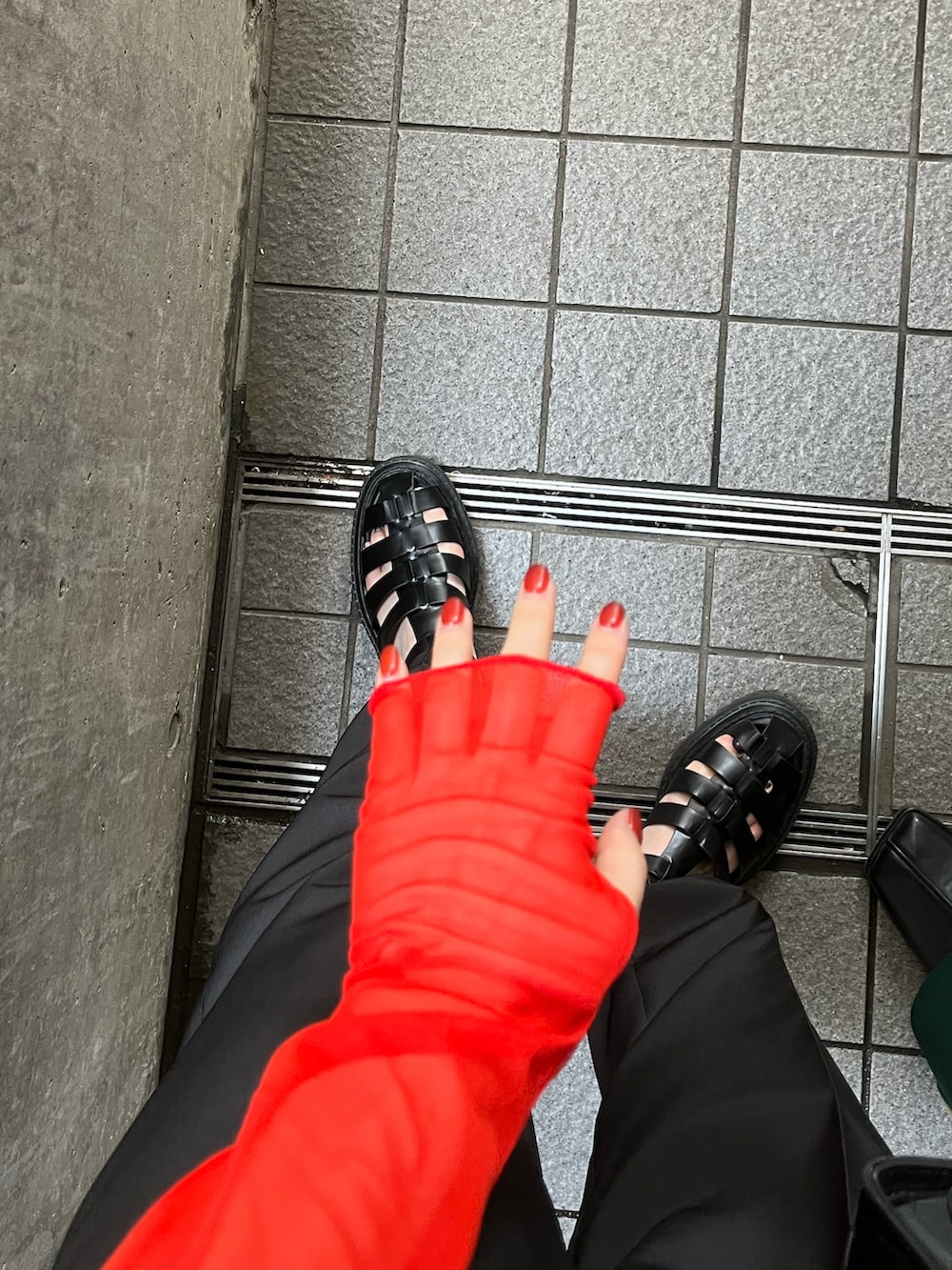 オレンジ系のTシャツ/カットソー、ブラック系のバッグ、ブラック系のスラックスを着用したレディースの夏コーディネートの4枚目の写真