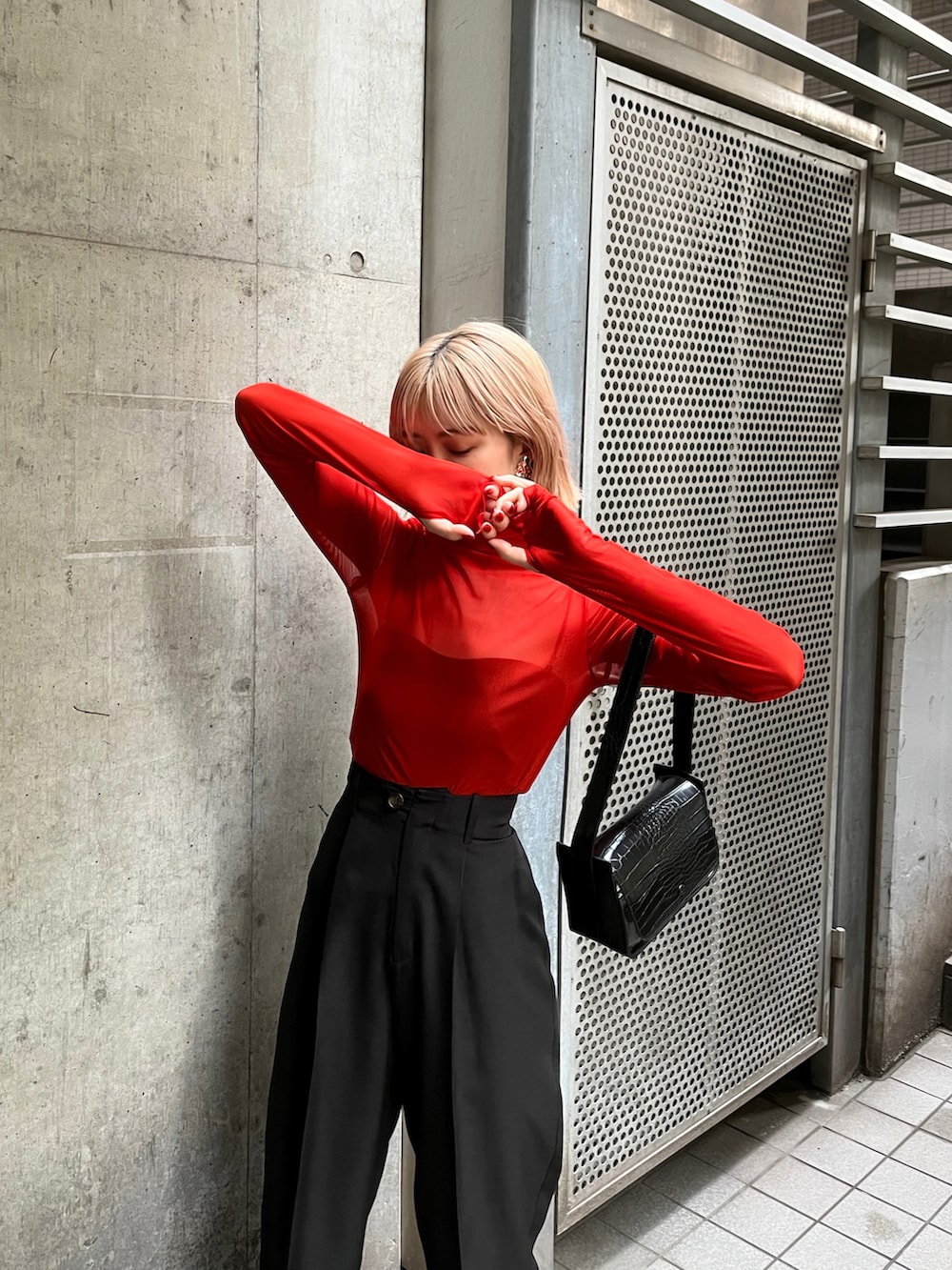 オレンジ系のTシャツ/カットソー、ブラック系のバッグ、ブラック系のスラックスを着用したレディースの夏コーディネートの2枚目の写真