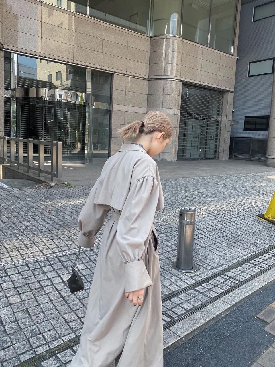 ベージュ系のトレンチコート、ホワイト系のブーツ、ブラック系のショルダーバッグを着用したレディースの春コーディネートの2枚目の写真