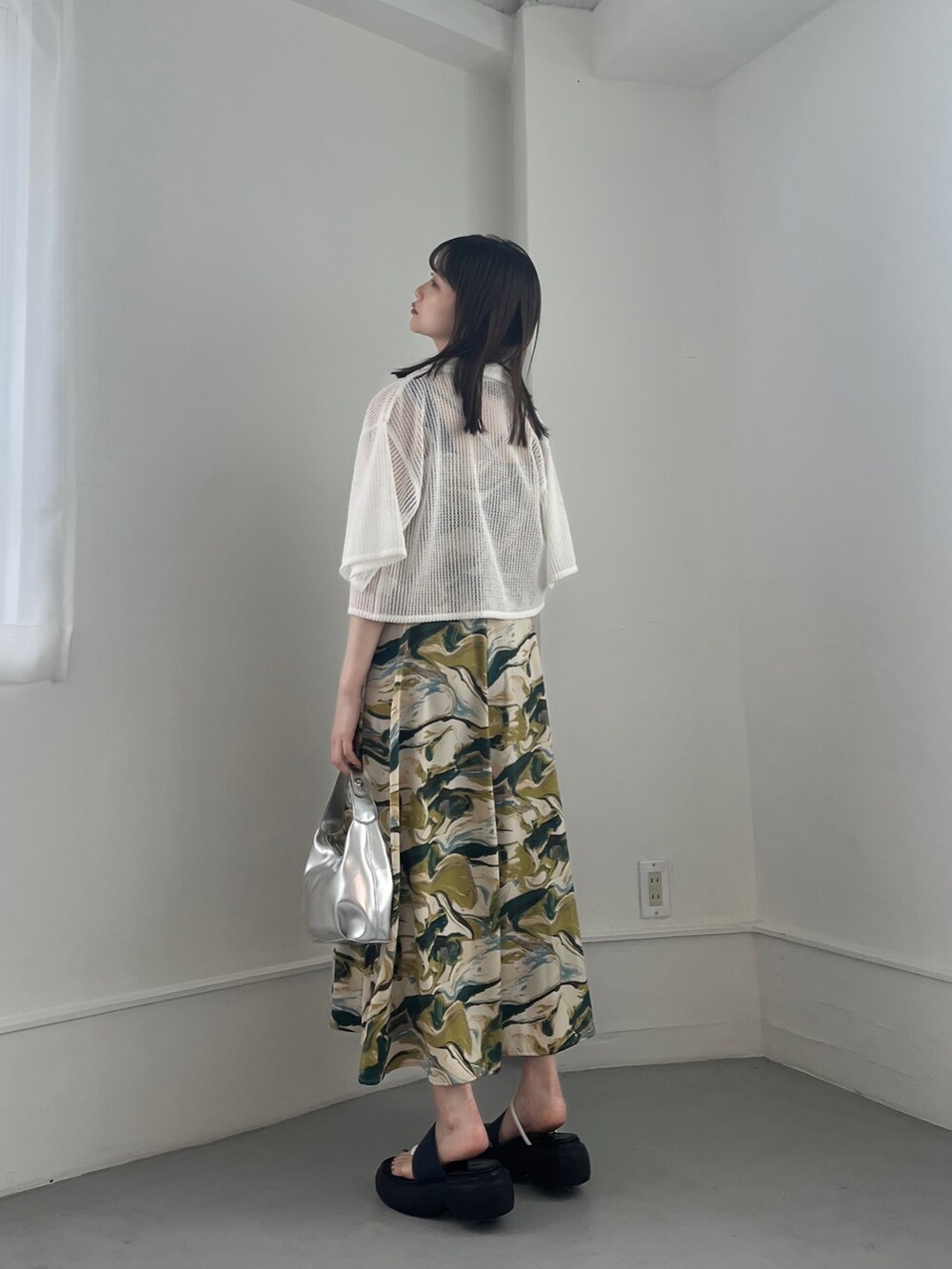 グリーン系のワンピース、ホワイト系のトップス、シルバー系のハンドバッグを着用したレディースの冬コーディネートの6枚目の写真