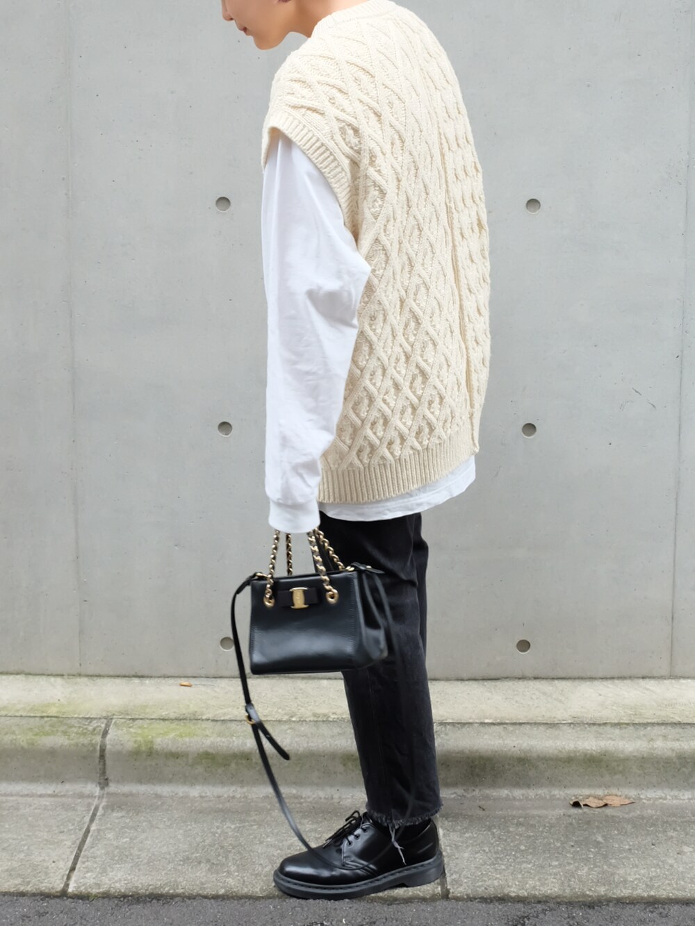 ホワイト系のベスト、ブラック系のハンドバッグ、ブラック系のブーツを着用したレディースの秋コーディネートの3枚目の写真