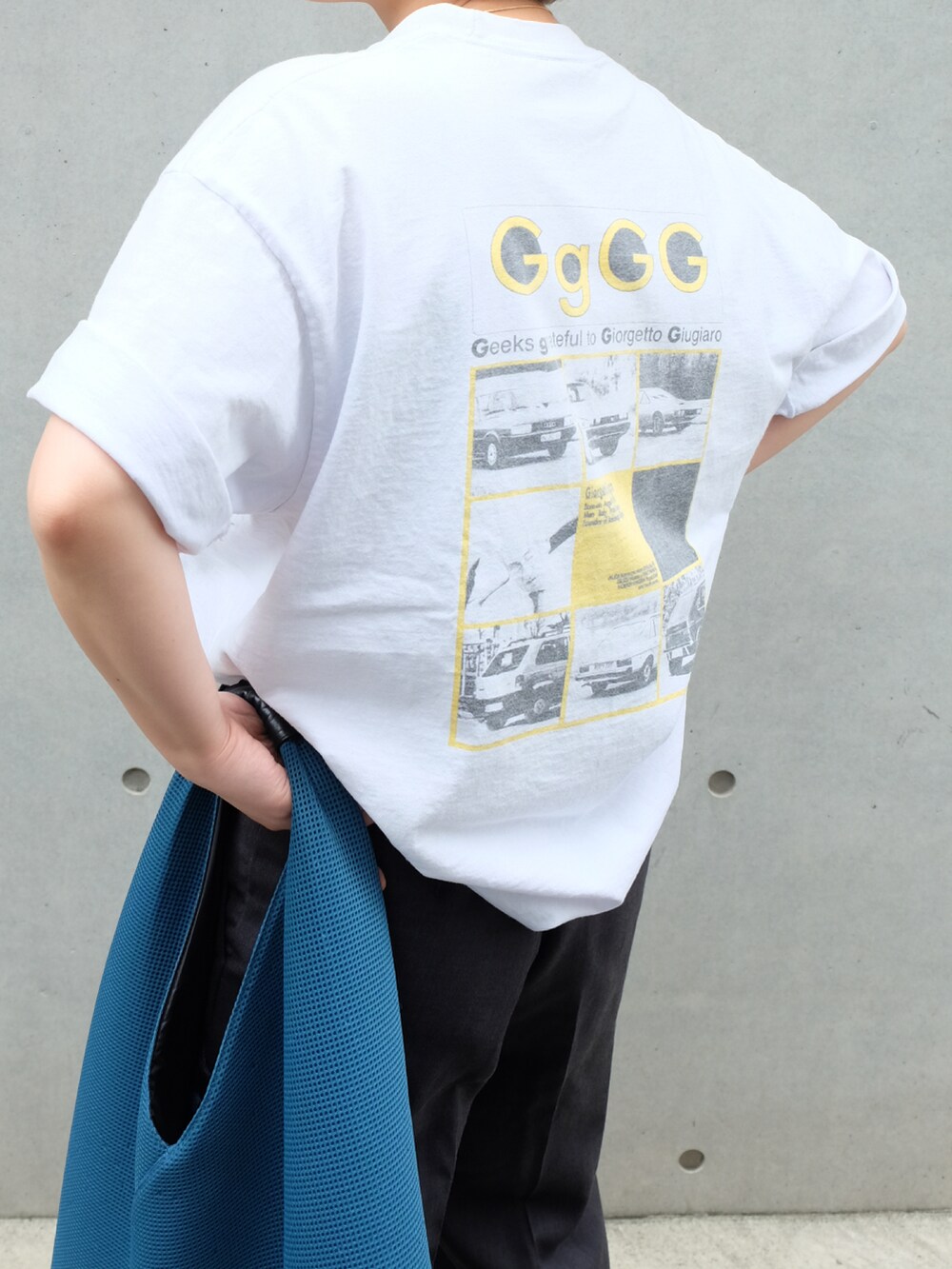 ブルー系のトートバッグ、ブラック系のサンダル、ホワイト系のTシャツ/カットソーを着用したレディースの夏コーディネートの4枚目の写真