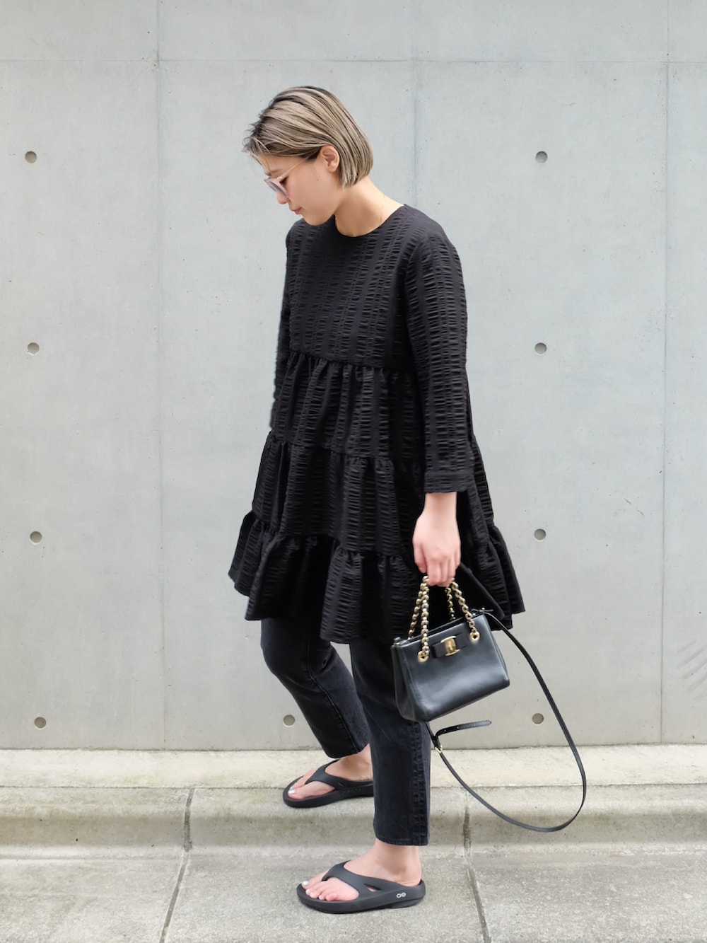 ブラック系のサンダル、ブラック系のハンドバッグ、ブラック系のデニムパンツを着用したレディースの夏コーディネートの2枚目の写真