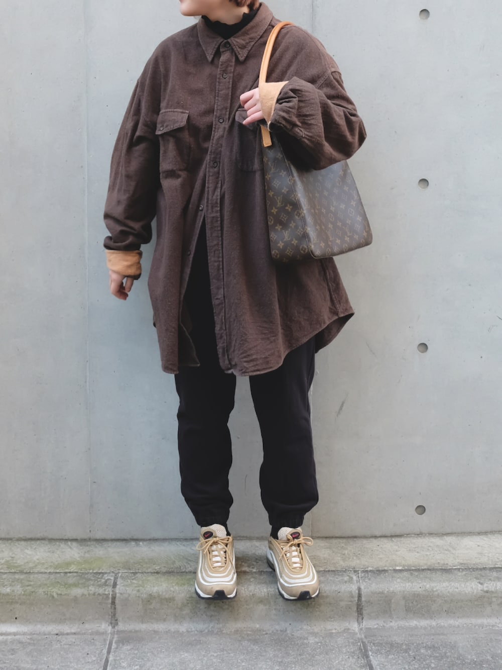 ゴールド系のスニーカー、ブラウン系のショルダーバッグ、ブラック系の帽子を着用したレディースの冬コーディネートの2枚目の写真