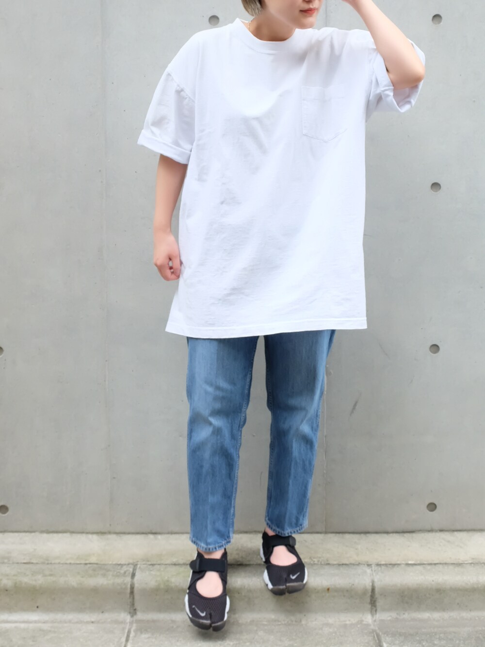 ブルー系のデニムパンツ、ホワイト系のTシャツ/カットソー、ブラック系のスニーカーを着用したレディースの夏コーディネートの2枚目の写真