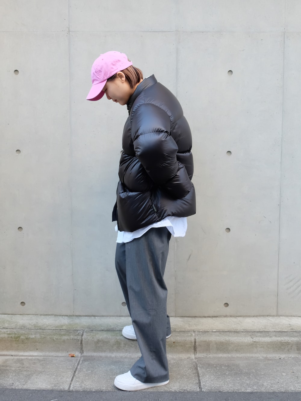 ホワイト系のスニーカー、ブラック系のダウンジャケット/コート、ピンク系のキャップを着用したレディースの冬コーディネートの2枚目の写真