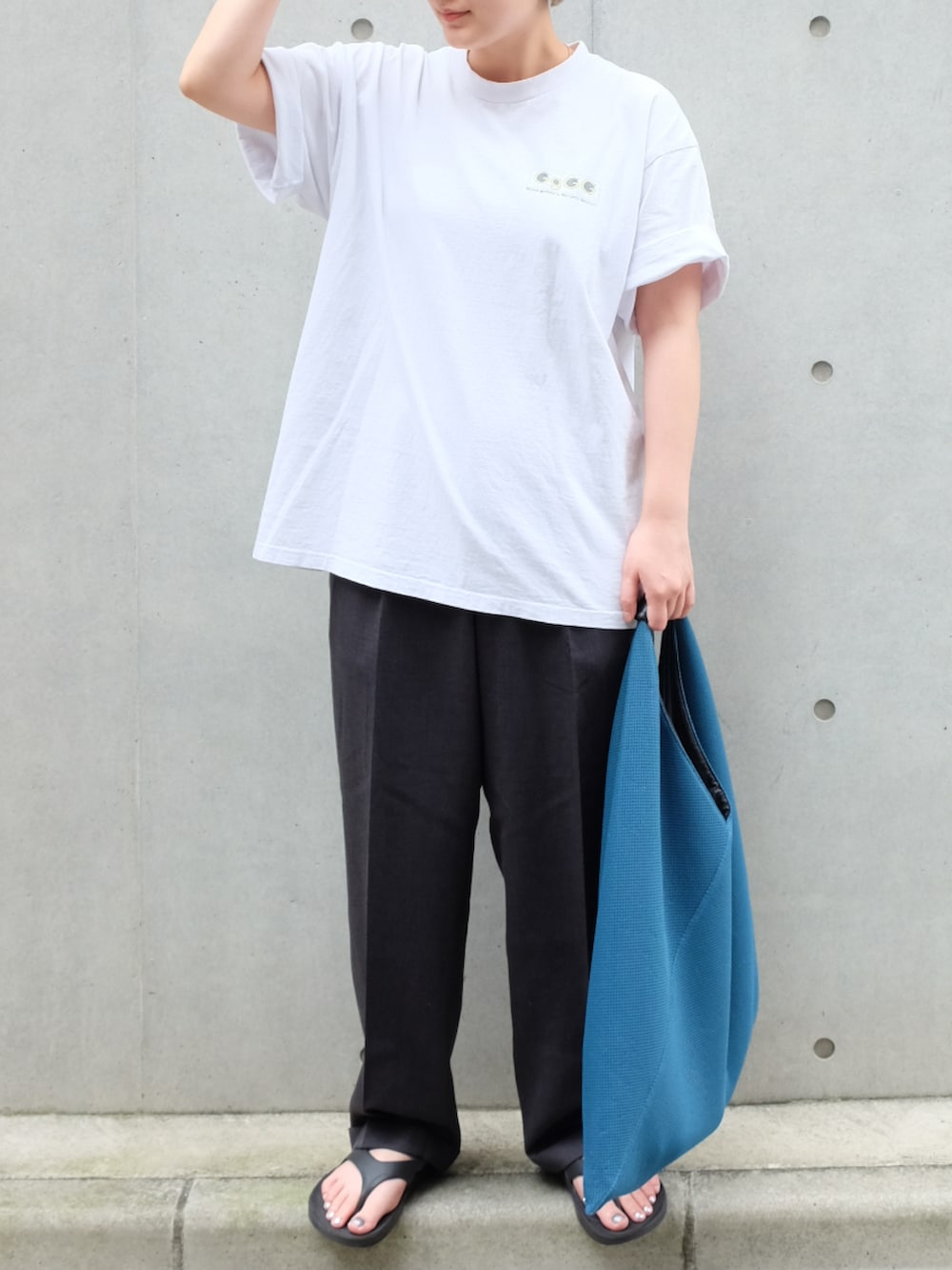 ブルー系のトートバッグ、ブラック系のサンダル、ホワイト系のTシャツ/カットソーを着用したレディースの夏コーディネートの3枚目の写真