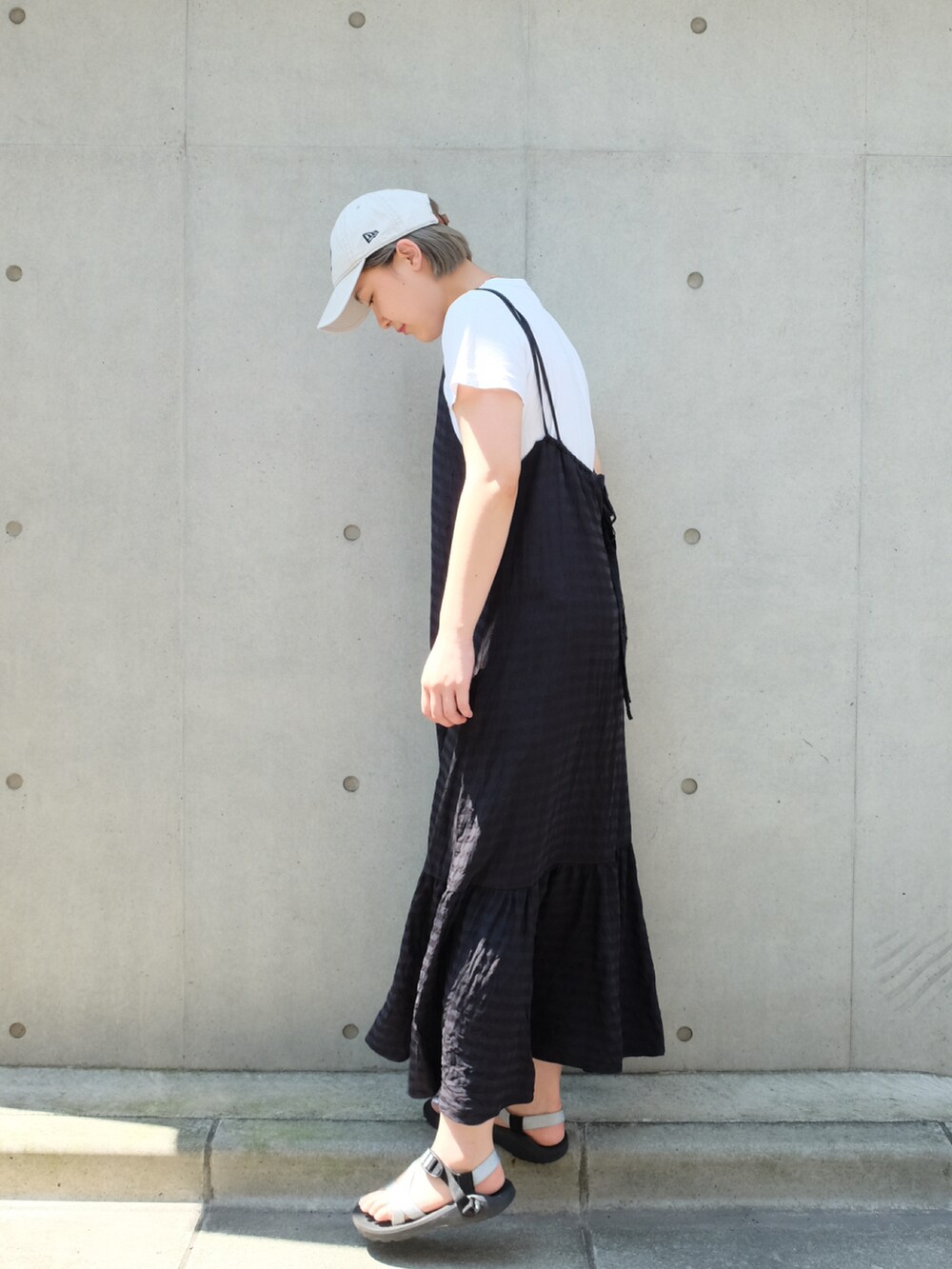 ブラック系のワンピース、ブラック系のサンダル、ホワイト系のTシャツ/カットソーを着用したレディースの夏コーディネートの2枚目の写真