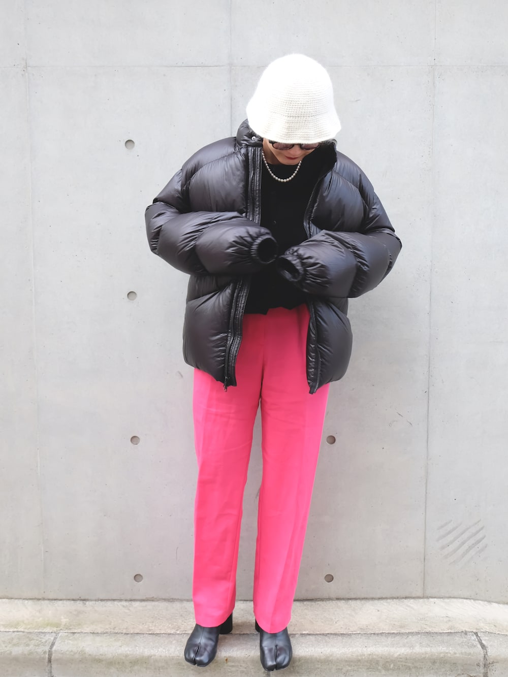 ブラック系のブーツ、ブラック系のダウンジャケット/コート、ピンク系のスラックスを着用したレディースの冬コーディネートの2枚目の写真