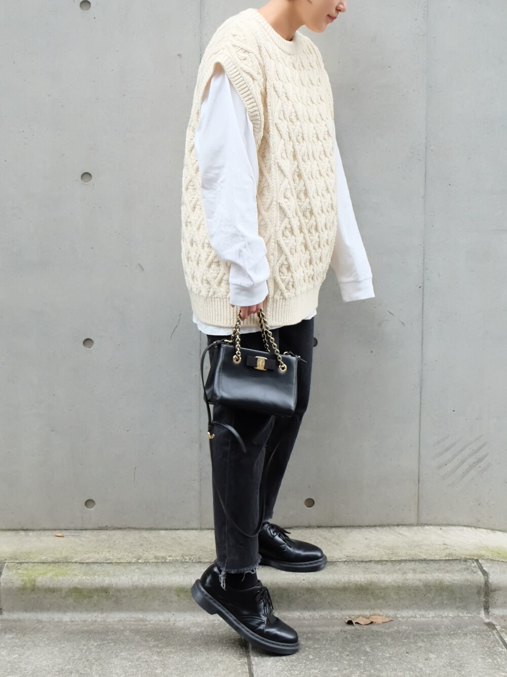 ホワイト系のベスト、ブラック系のハンドバッグ、ブラック系のブーツを着用したレディースの秋コーディネートの2枚目の写真