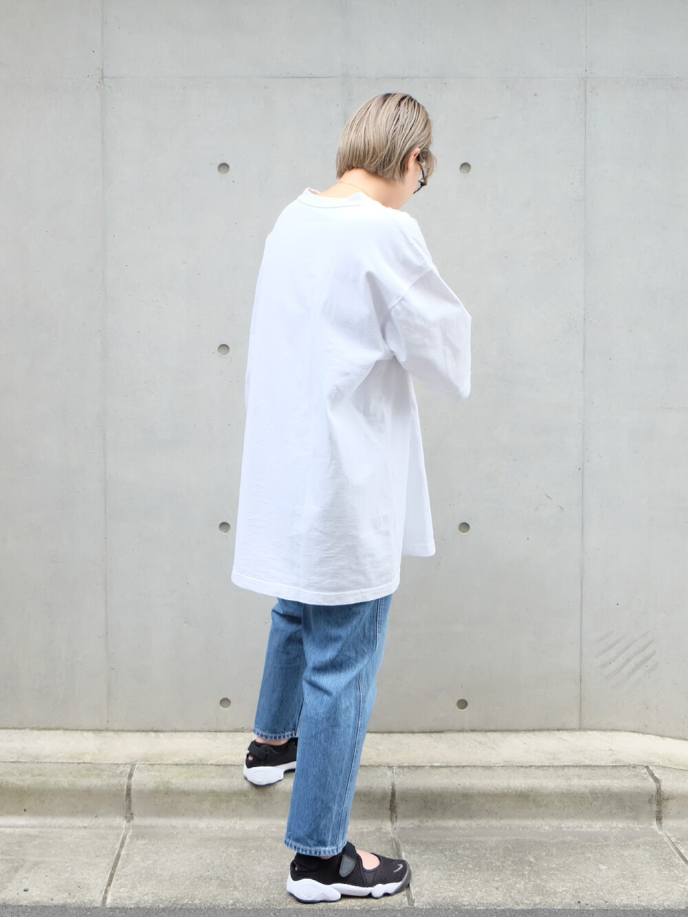 ブルー系のデニムパンツ、ホワイト系のTシャツ/カットソー、ブラック系のスニーカーを着用したレディースの夏コーディネートの3枚目の写真