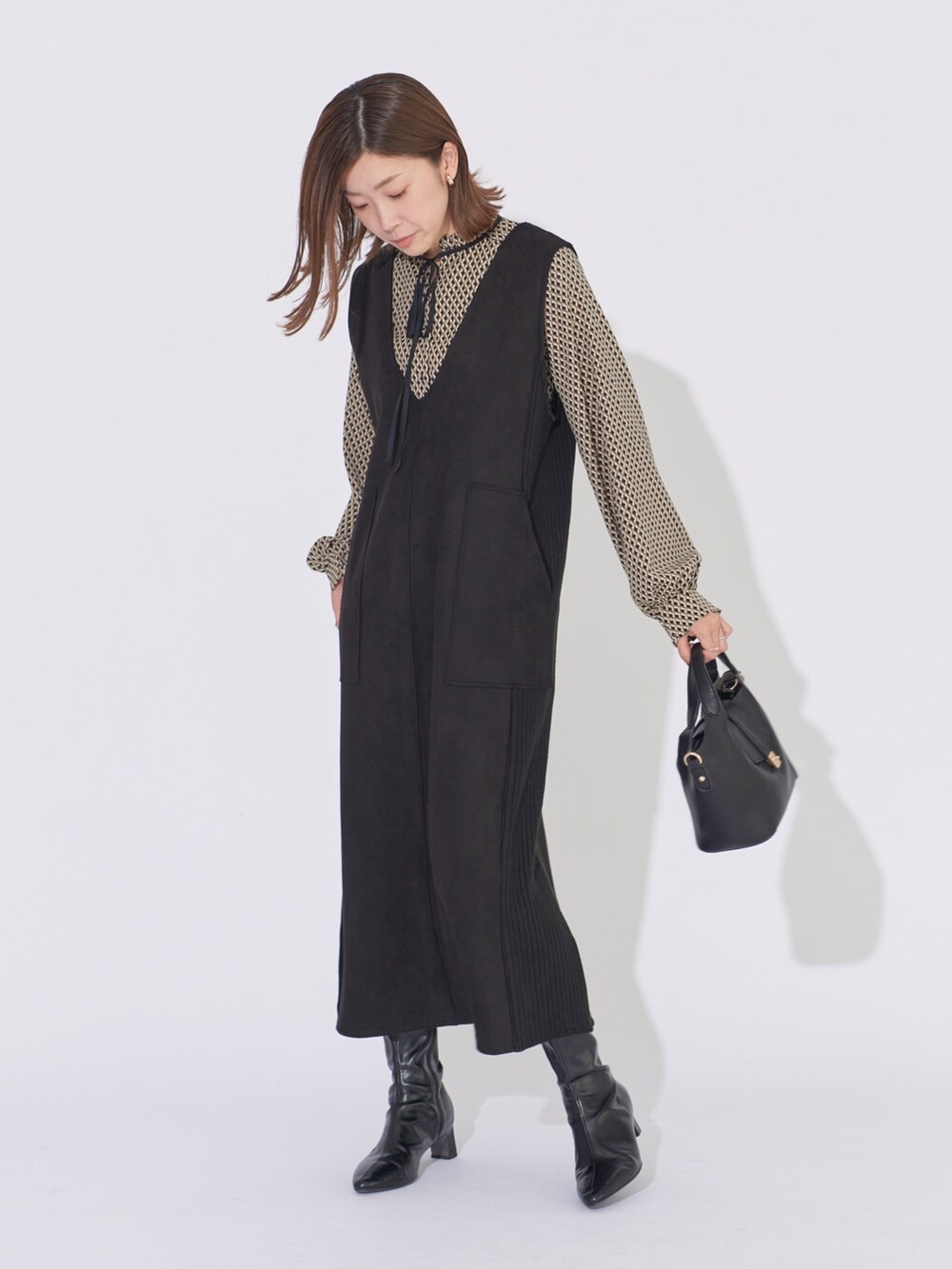 ブラック系のジャンパースカート、ブラック系のシャツ/ブラウス、ブラック系のハンドバッグを着用したレディースの冬コーディネートの2枚目の写真