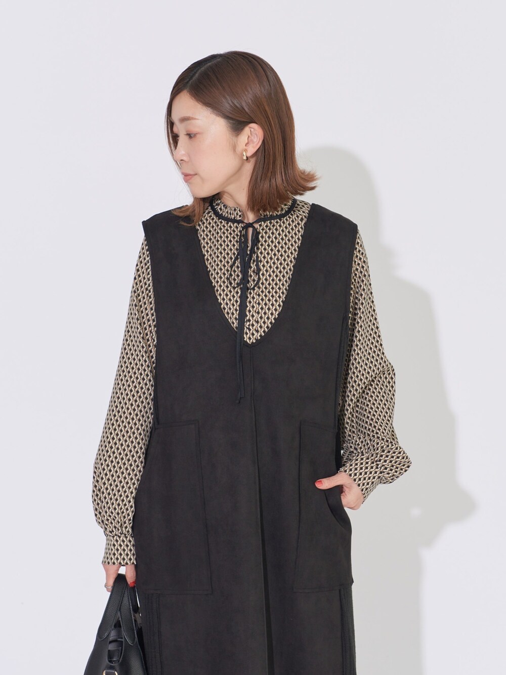 ブラック系のジャンパースカート、ブラック系のシャツ/ブラウス、ブラック系のハンドバッグを着用したレディースの冬コーディネートの3枚目の写真