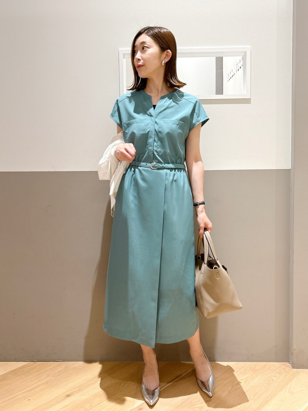 グリーン系のワンピース、ホワイト系のカーディガン/ボレロ、シルバー系のパンプスを着用したレディースの夏コーディネートの2枚目の写真